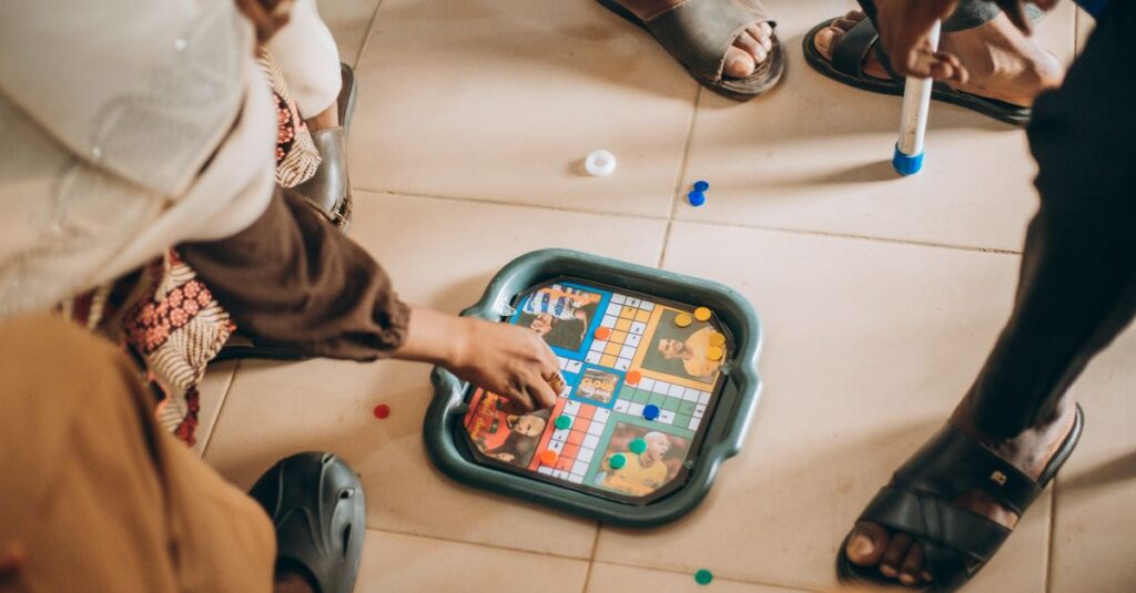 年齢問わず家族全員が大笑いしながらボードゲームを楽しんでいるシーン。世代を超えて盛り上がる瞬間。