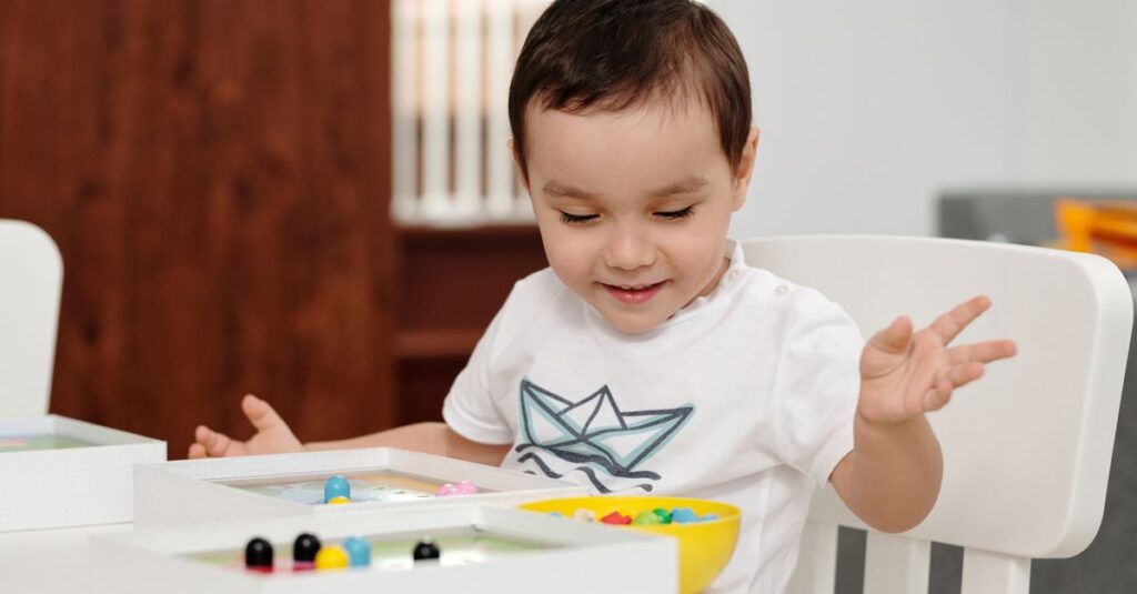 3歳から6歳の子どもが簡単なルールのボードゲームを楽しんでいる様子。親と一緒に笑顔でプレイ中。