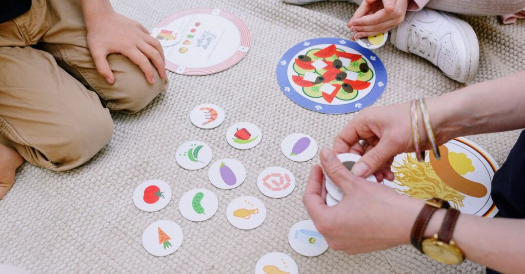 幼児向けのボードゲームを家族で楽しむ様子。カラフルなカードと笑顔あふれる子どもの表情が特徴