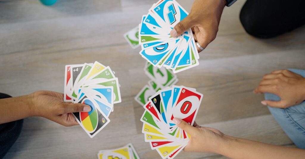 短時間で遊べるカードゲームを家族で楽しんでいる様子。テーブルの上にカードが広がり、笑顔で対話しながら遊ぶシーン。