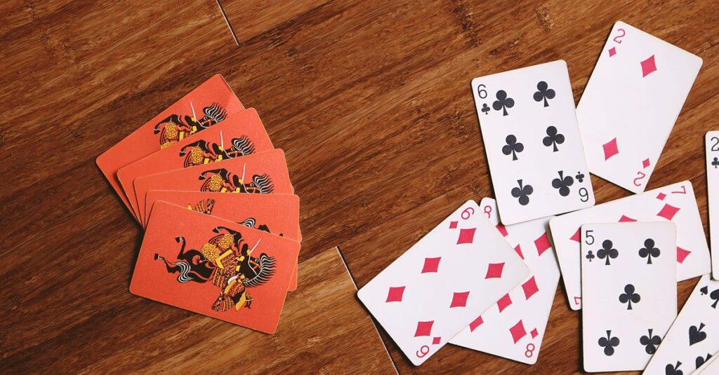 5人以上の家族がリビングでパーティーゲームを楽しんでいる。輪になって笑顔で話し合いながらカードをめくっている様子。