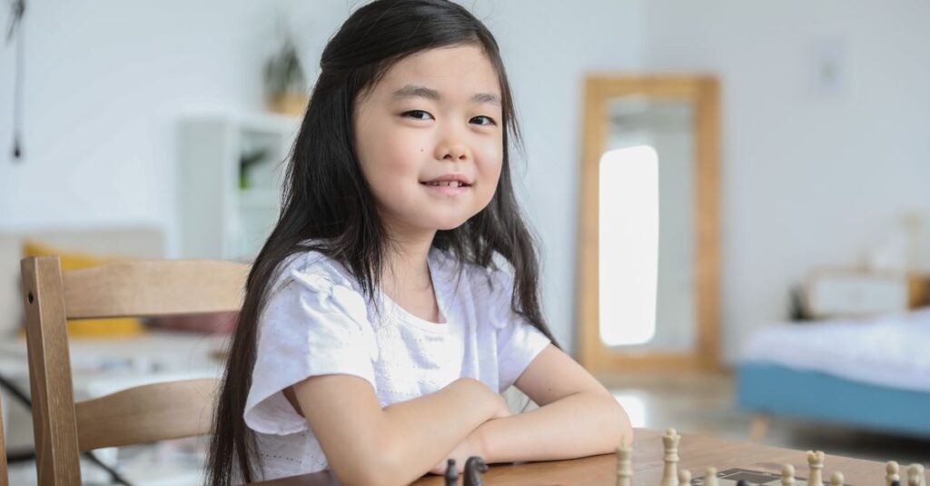 小学生の女の子が友達や親と一緒にボードゲームを楽しんでいる。カラフルでかわいいゲームが並んでいる