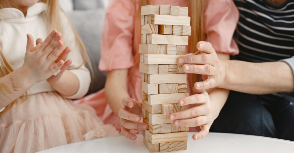 道具なしで室内ゲームを楽しむ家族。子どもと大人が笑顔でジェスチャーや言葉遊びをしている16:9のシーン。
